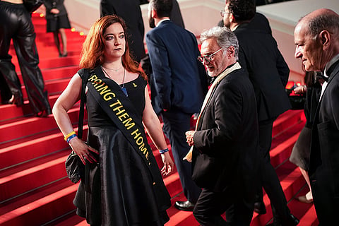 A person wears a sash with "Bring them home" during 'The Shrouds' premiere